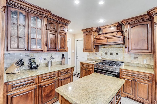 13514 King Phillip Ct, Corpus Christi, TX 78418 - kitchen with stainless steel range with gas stovetop, glass insert cabinets, recessed lighting, tasteful backsplash, and custom range hood