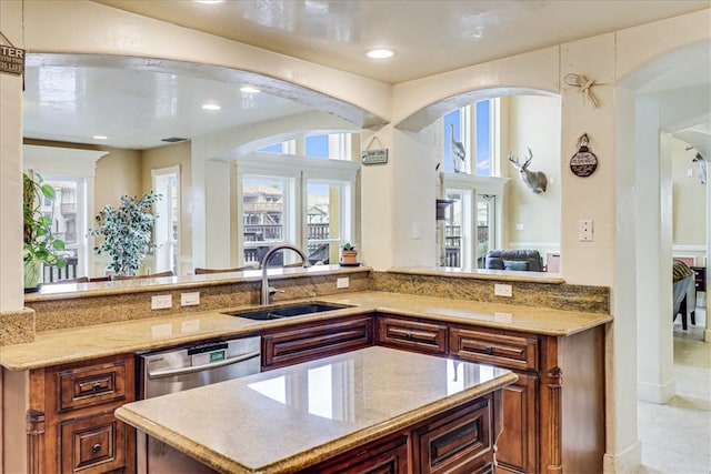 kitchen with stainless steel dishwasher, light stone countertops, light tile patterned floors, and sink