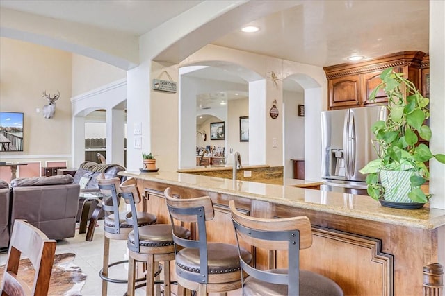 13514 King Phillip Ct, Corpus Christi, TX 78418 - bar with stainless steel refrigerator with ice dispenser, light tile patterned floors, recessed lighting, and arched walkways