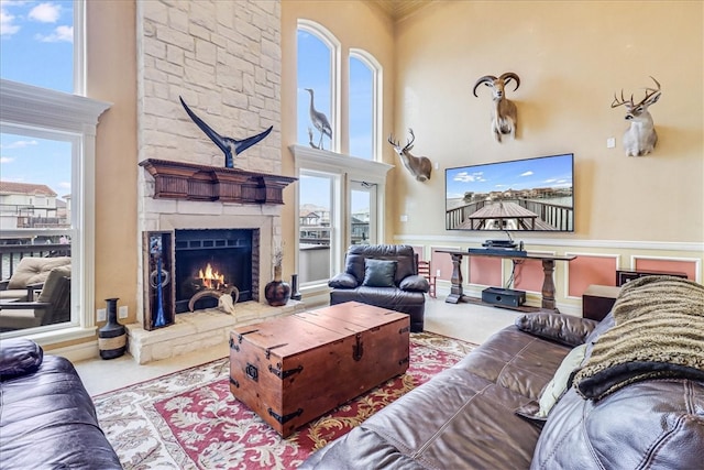 living room with a high ceiling, a stone fireplace, and carpet