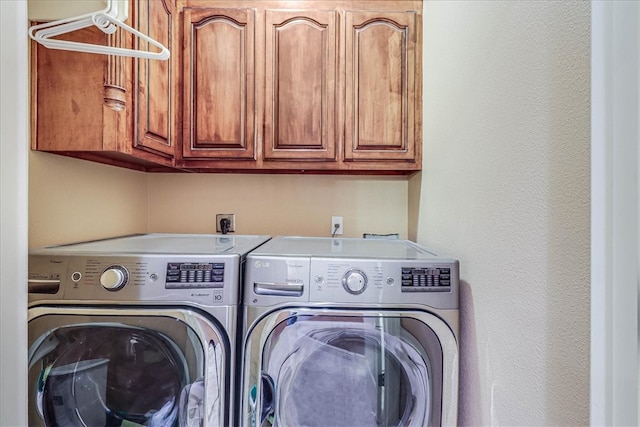 clothes washing area with cabinets and washing machine and dryer