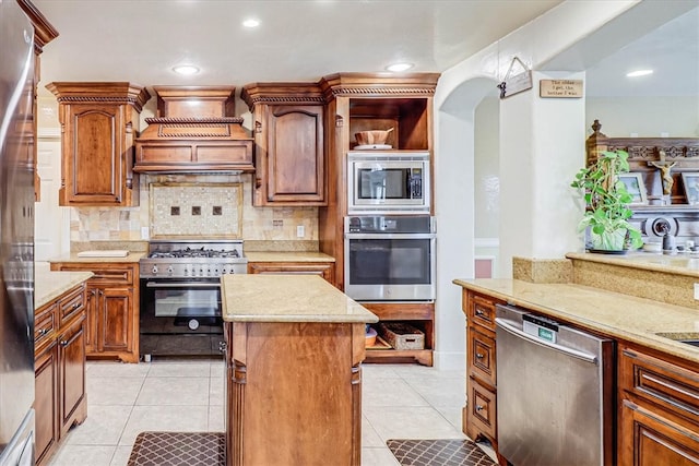 kitchen with stainless steel appliances, custom range hood, light tile patterned floors, decorative backsplash, and a center island