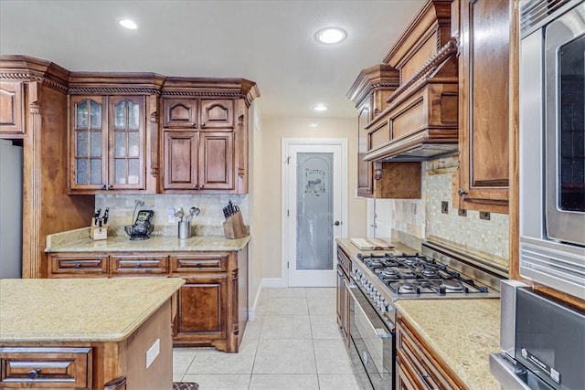 13514 King Phillip Ct, Corpus Christi, TX 78418 - kitchen featuring gas range, baseboards, tasteful backsplash, light tile patterned flooring, and glass insert cabinets
