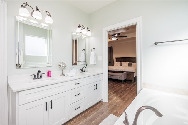 bathroom with hardwood / wood-style floors, a washtub, ceiling fan, and vanity