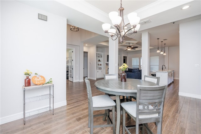 dining area with ceiling fan with notable chandelier, light hardwood / wood-style flooring, and sink