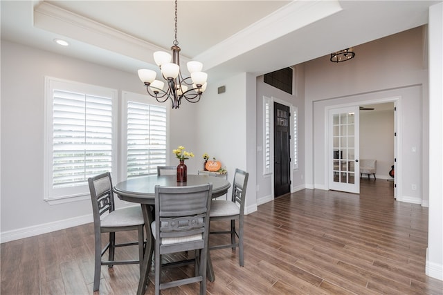 dining space featuring french doors, dark wood-type flooring, a notable chandelier, crown molding, and a tray ceiling