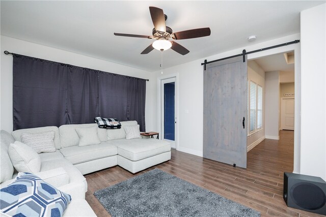 living room with a barn door, ceiling fan, and dark hardwood / wood-style flooring