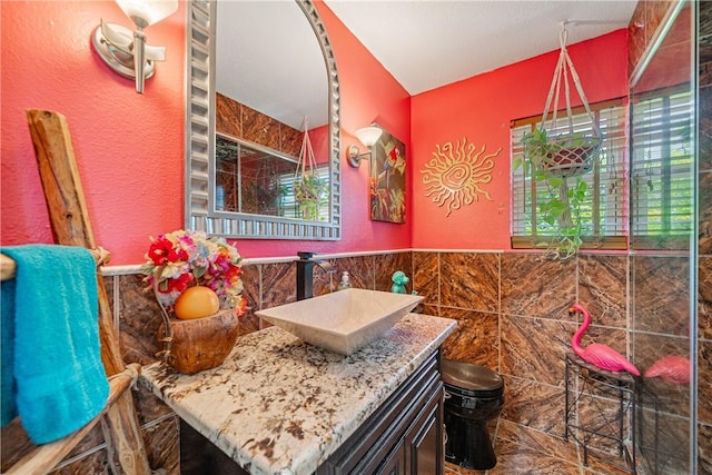 15718 Escapade St, Corpus Christi, TX 78418 - bathroom with vanity, a textured wall, tile walls, and a wainscoted wall