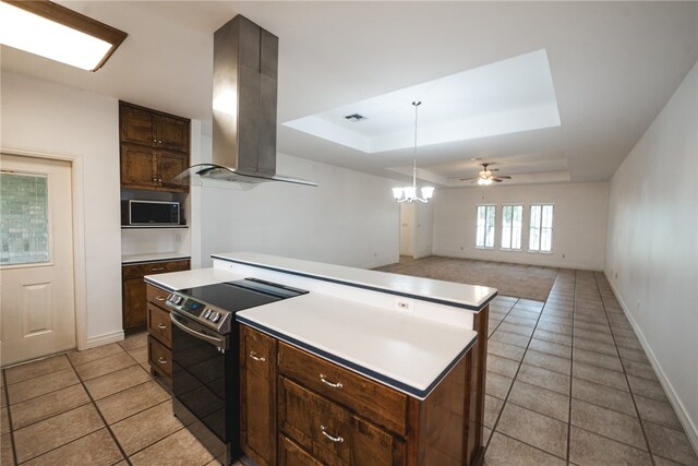 kitchen with electric range oven, ceiling fan with notable chandelier, a tray ceiling, a center island, and island exhaust hood