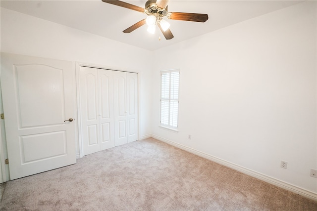 unfurnished bedroom featuring light carpet, ceiling fan, and a closet