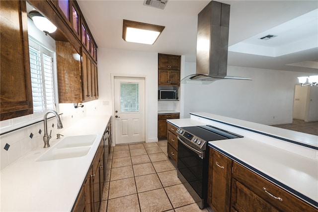 kitchen with stainless steel microwave, sink, light tile patterned floors, range with electric stovetop, and island exhaust hood