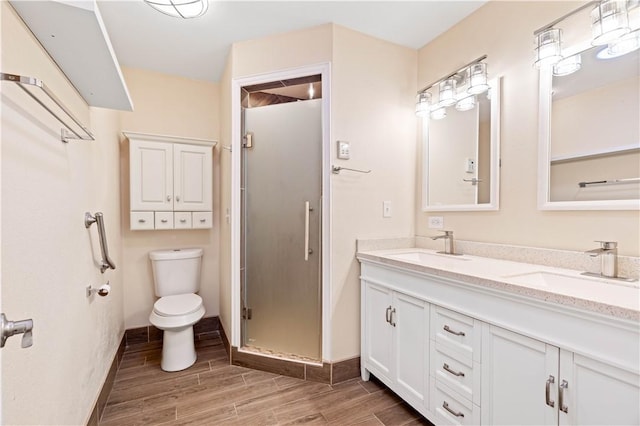 full bath with toilet, wood tiled floor, a sink, and a shower stall