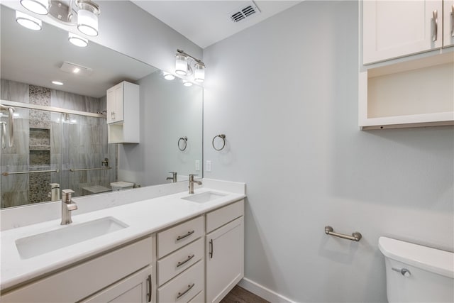 bathroom with toilet, vanity, and a shower with shower door