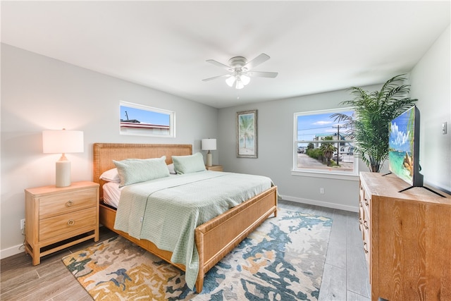 bedroom featuring light wood-type flooring, multiple windows, and ceiling fan