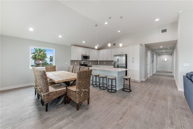 dining room with light hardwood / wood-style floors, lofted ceiling, and sink