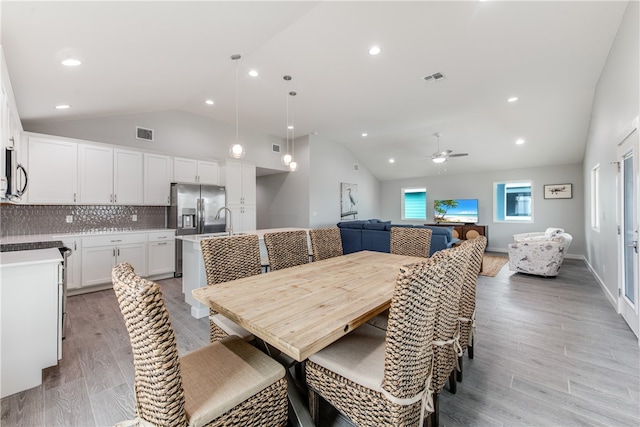 dining room featuring light hardwood / wood-style floors, ceiling fan, sink, and lofted ceiling