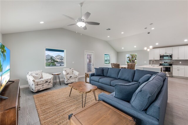 living room featuring light wood-type flooring, vaulted ceiling, and ceiling fan