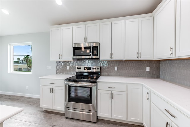 kitchen with white cabinets, appliances with stainless steel finishes, and light hardwood / wood-style flooring