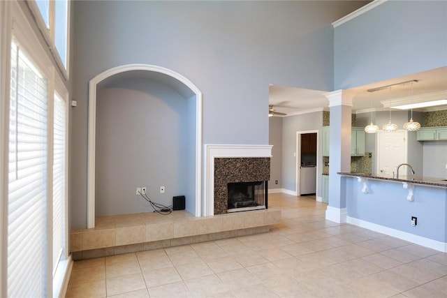 5710 Neustadt Dr, Corpus Christi, TX 78414 - unfurnished living room featuring a ceiling fan, a high ceiling, light tile patterned flooring, a tiled fireplace, and a sink
