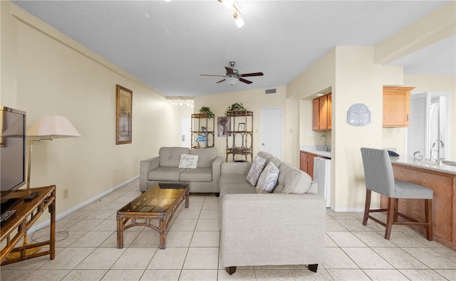 tiled living room with ceiling fan, sink, and a textured ceiling