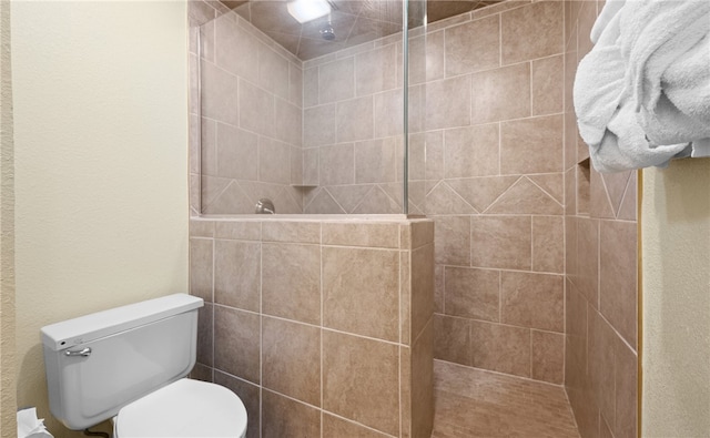 bathroom with a tile shower and toilet