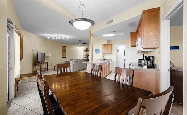 dining space with ceiling fan, sink, light tile patterned floors, and a textured ceiling