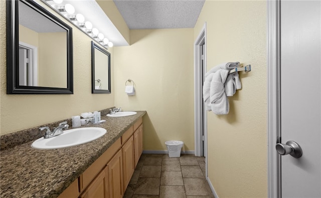 bathroom with tile patterned flooring, vanity, and a textured ceiling