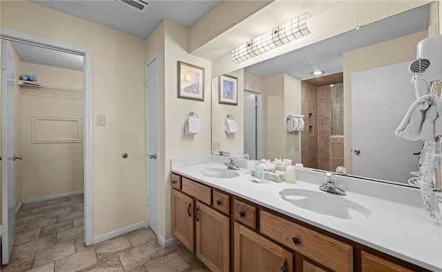 bathroom with a tile shower, vanity, and a textured ceiling