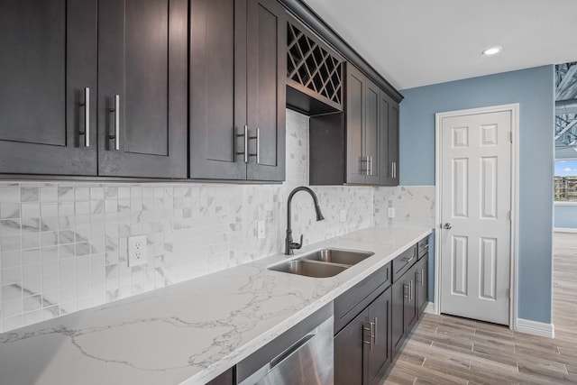 kitchen featuring decorative backsplash, sink, light hardwood / wood-style flooring, and light stone counters