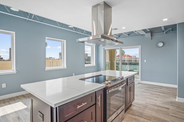 kitchen featuring island exhaust hood, a healthy amount of sunlight, light hardwood / wood-style flooring, and electric range