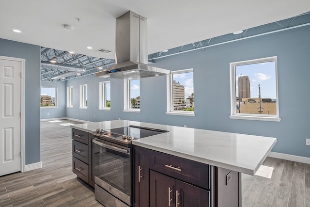 kitchen with island range hood, stainless steel range with electric stovetop, light hardwood / wood-style floors, and plenty of natural light