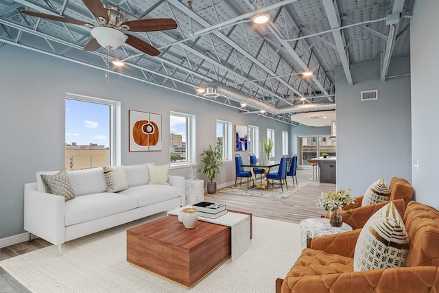 living room with hardwood / wood-style floors, ceiling fan, and a towering ceiling