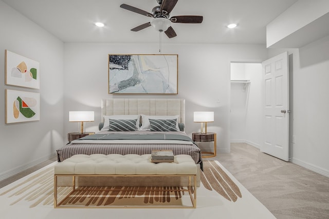 bedroom with ceiling fan, light colored carpet, a closet, and a spacious closet