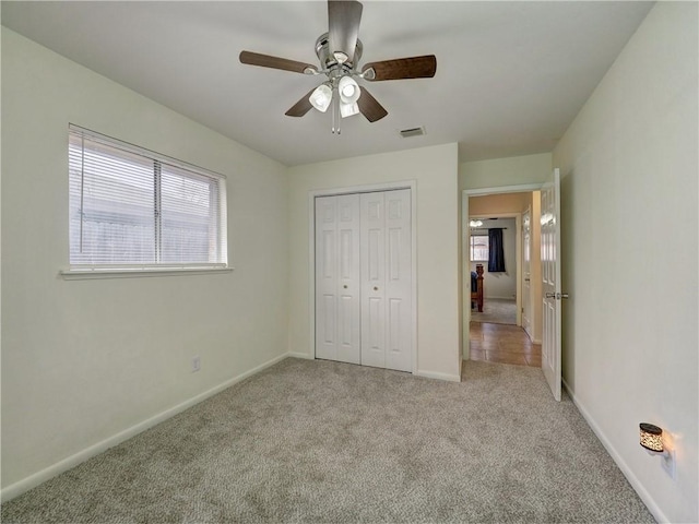 unfurnished bedroom with light colored carpet, a closet, and ceiling fan