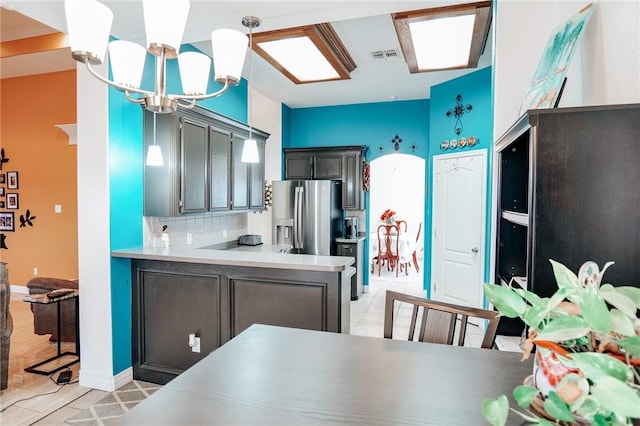 kitchen featuring decorative light fixtures, a chandelier, stainless steel fridge with ice dispenser, kitchen peninsula, and decorative backsplash