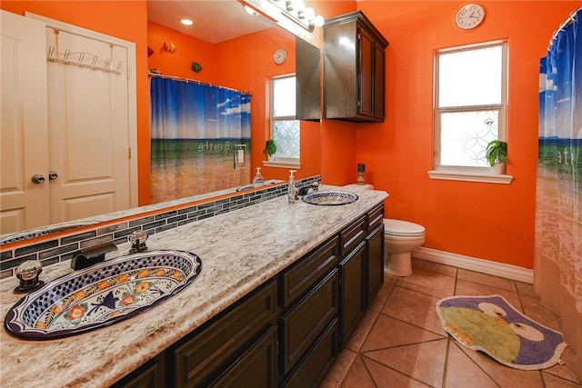 bathroom with tile patterned flooring, vanity, a healthy amount of sunlight, and toilet