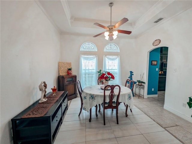 dining room featuring a raised ceiling, ornamental molding, light tile patterned floors, and ceiling fan