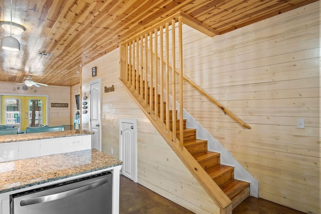 staircase with concrete flooring, wooden walls, french doors, and wooden ceiling