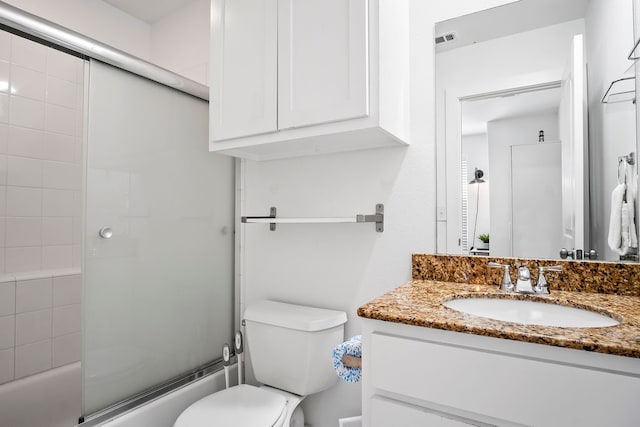 full bathroom with bath / shower combo with glass door, vanity, and toilet