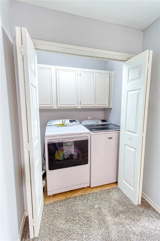 laundry area with washer and clothes dryer, cabinets, and light colored carpet