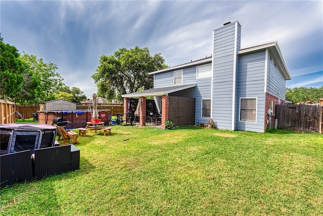 back of property with an outdoor fire pit and a yard