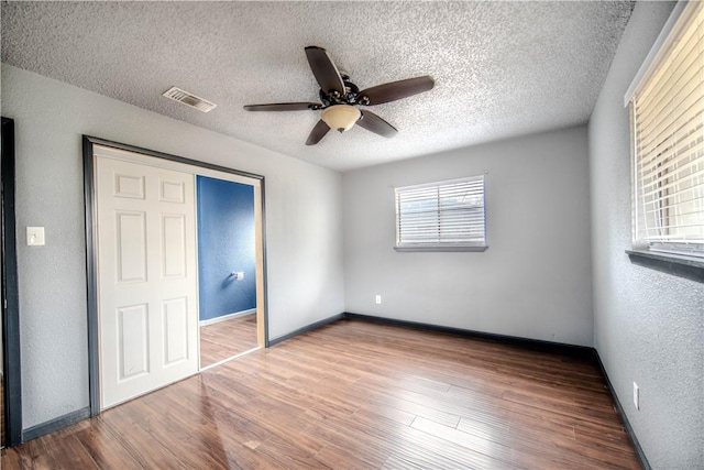 unfurnished bedroom featuring ceiling fan, hardwood / wood-style floors, and a textured ceiling