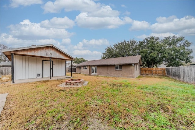 rear view of property with a patio, a yard, and an outdoor fire pit