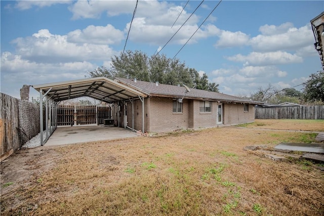 back of property with a carport, a patio area, and a lawn