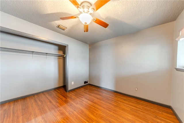 unfurnished bedroom featuring ceiling fan, hardwood / wood-style floors, a closet, and a textured ceiling