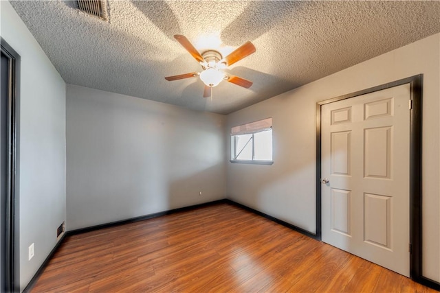 spare room with hardwood / wood-style floors, a textured ceiling, and ceiling fan