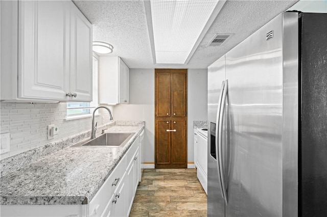 1729 Mermaid Dr, Corpus Christi, TX 78412 - kitchen with stainless steel fridge with ice dispenser, a sink, light wood-type flooring, tasteful backsplash, and white cabinets