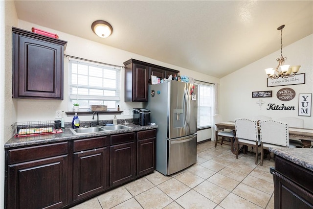 kitchen with lofted ceiling, sink, stainless steel fridge, light tile patterned flooring, and dark brown cabinets