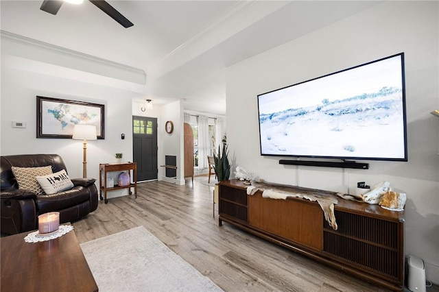 living room featuring baseboards, ceiling fan, ornamental molding, and light wood-style flooring