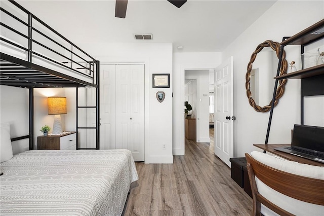 bedroom featuring visible vents, a closet, wood finished floors, baseboards, and a ceiling fan